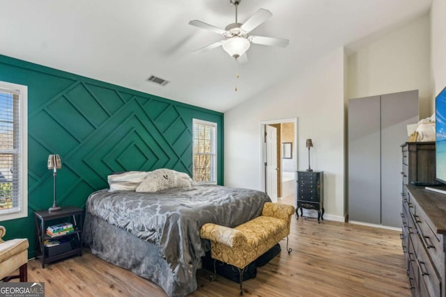 bedroom featuring light wood-type flooring, ceiling fan, vaulted ceiling, and ensuite bath