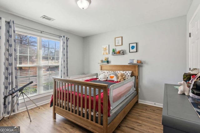 bedroom featuring multiple windows and dark hardwood / wood-style flooring