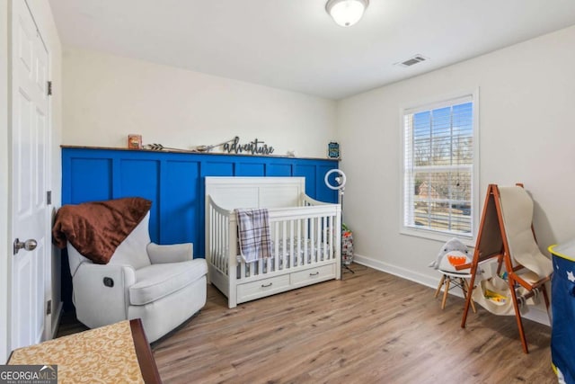 bedroom with wood-type flooring and a nursery area