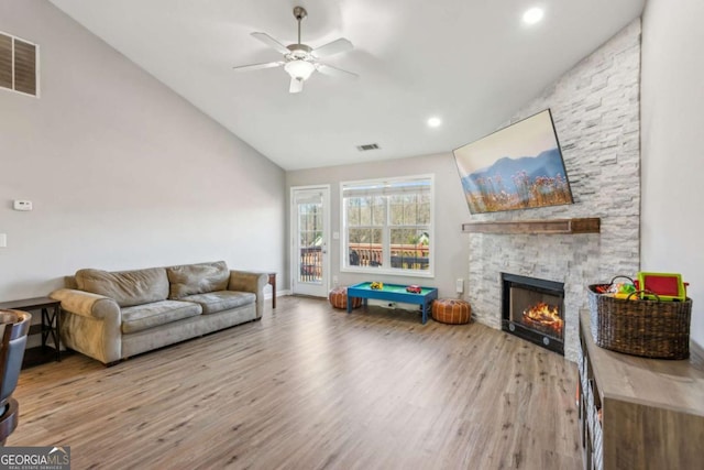 living room featuring vaulted ceiling, ceiling fan, a fireplace, and hardwood / wood-style flooring