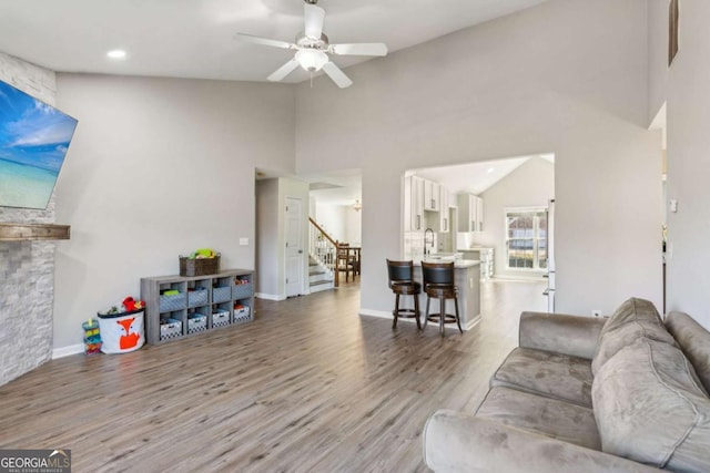 living room with sink, ceiling fan, a high ceiling, and light hardwood / wood-style flooring