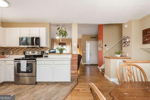 kitchen featuring white cabinets, backsplash, appliances with stainless steel finishes, and light wood-type flooring