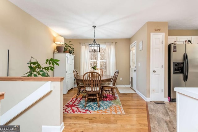 dining room with light wood-type flooring and an inviting chandelier