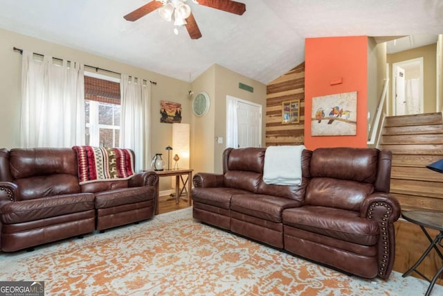 living room with ceiling fan, wooden walls, and lofted ceiling