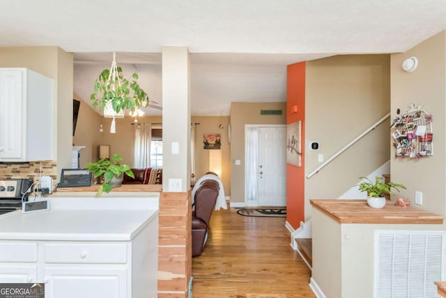 kitchen with kitchen peninsula, white cabinets, decorative backsplash, and light hardwood / wood-style floors