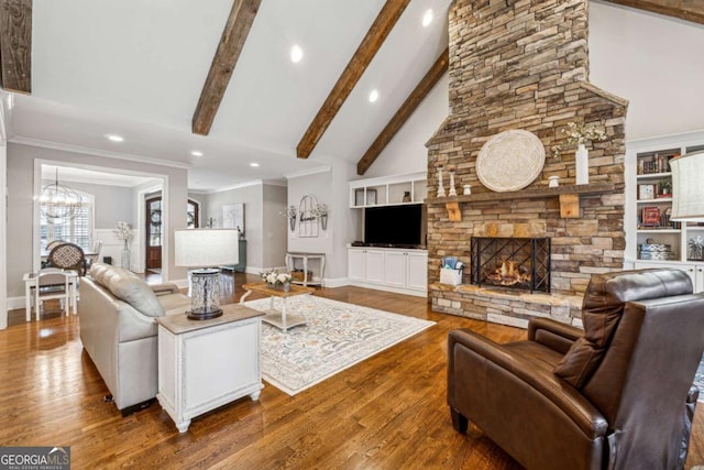 living room with wood-type flooring, built in features, a stone fireplace, high vaulted ceiling, and beamed ceiling