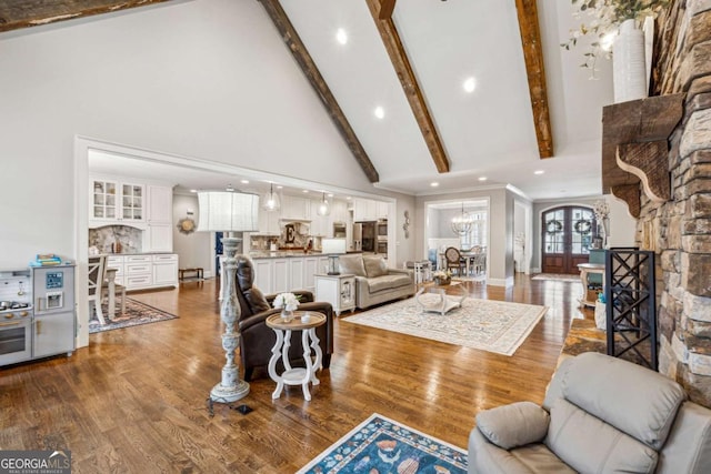 living room with hardwood / wood-style flooring, a chandelier, high vaulted ceiling, french doors, and beam ceiling