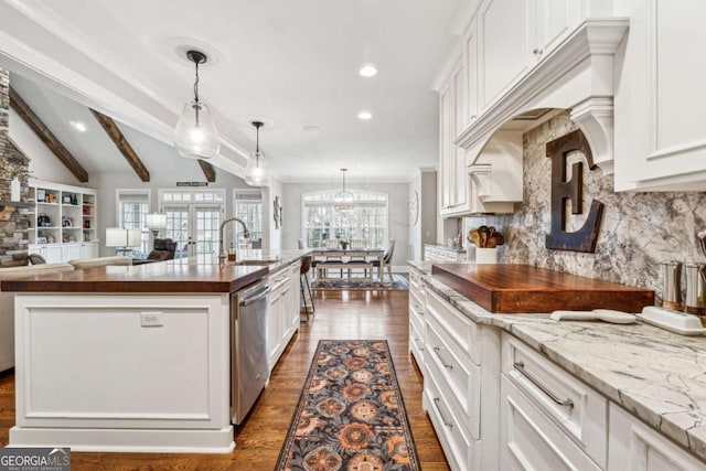 kitchen with white cabinetry, stainless steel dishwasher, decorative backsplash, sink, and a center island with sink