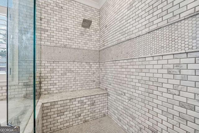 bathroom with crown molding and a tile shower