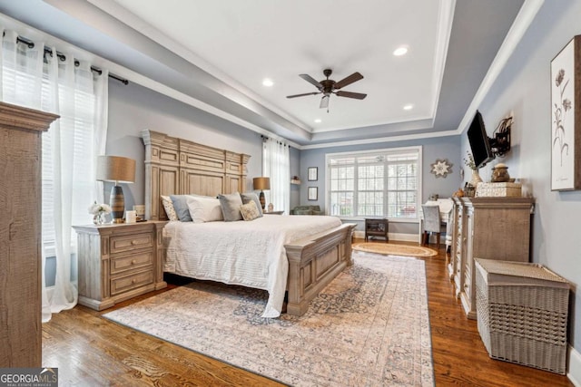 bedroom featuring ceiling fan, hardwood / wood-style flooring, a tray ceiling, and ornamental molding