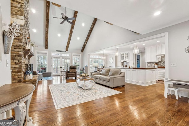 living room with hardwood / wood-style flooring, high vaulted ceiling, french doors, beam ceiling, and ceiling fan