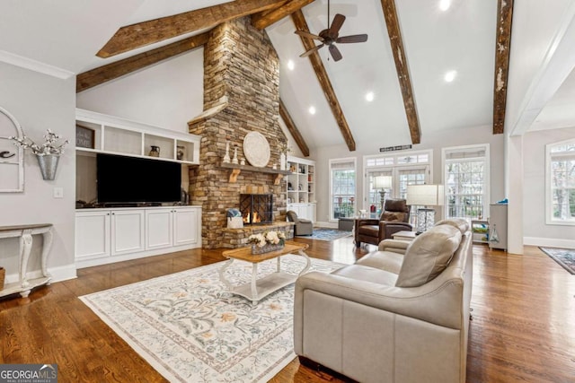 living room with wood-type flooring, ceiling fan, beam ceiling, a fireplace, and high vaulted ceiling