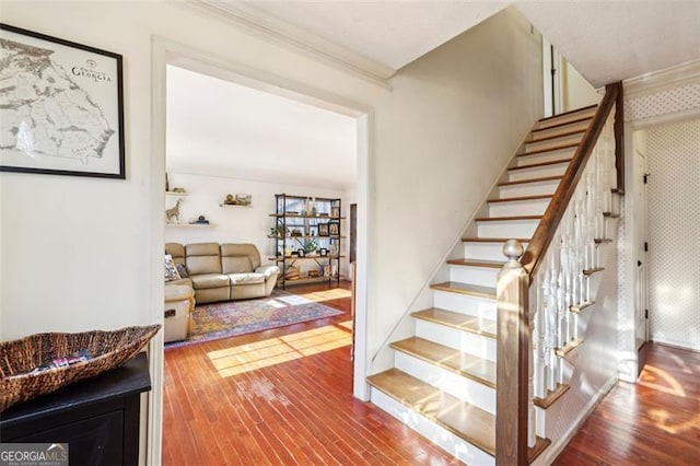 stairs with wood-type flooring and crown molding