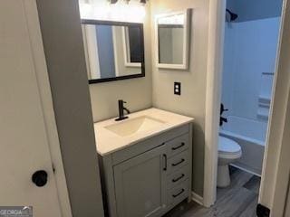 full bathroom with  shower combination, hardwood / wood-style flooring, toilet, and vanity