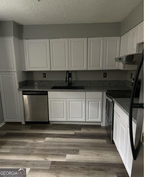 kitchen with black appliances, white cabinetry, a textured ceiling, and sink