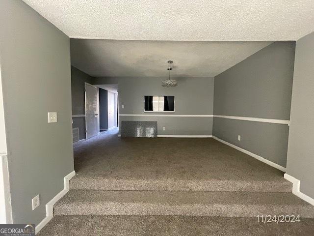 stairs featuring a textured ceiling and carpet flooring