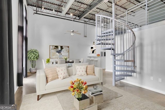 living room featuring concrete flooring, a high ceiling, and ceiling fan