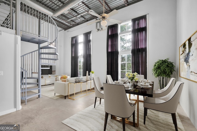 dining area featuring concrete floors, a high ceiling, and ceiling fan