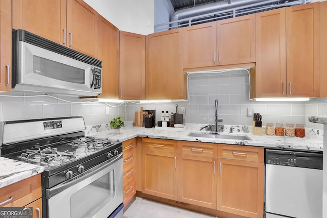 kitchen with light stone counters, sink, stainless steel appliances, and tasteful backsplash