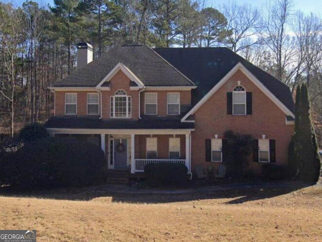 colonial house featuring a front yard and covered porch