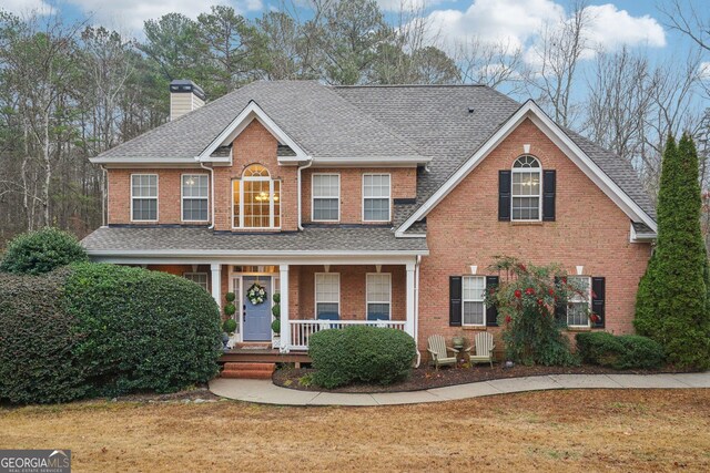 colonial house featuring a front yard and covered porch