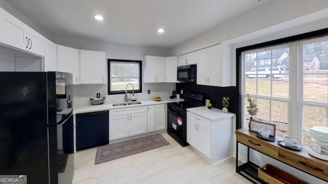 kitchen with sink, black appliances, and white cabinets