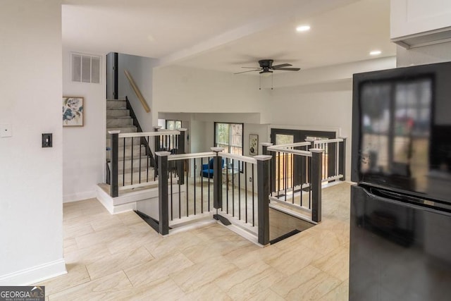 interior space featuring ceiling fan, white cabinetry, and black fridge