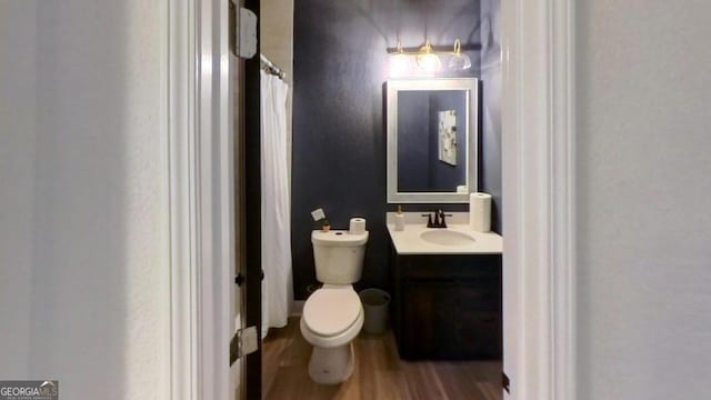 bathroom with wood-type flooring, toilet, and vanity