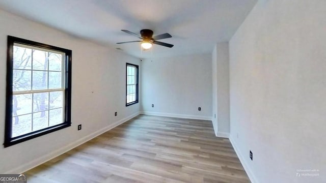 spare room featuring a healthy amount of sunlight, ceiling fan, and light hardwood / wood-style floors