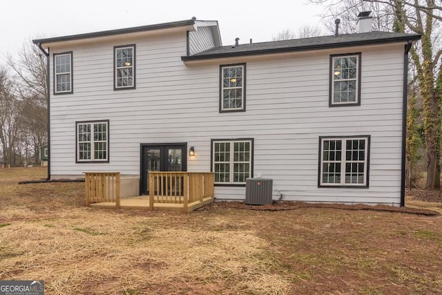 rear view of house with cooling unit, french doors, and a lawn