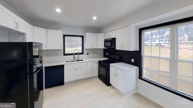 kitchen with black appliances, white cabinets, and sink