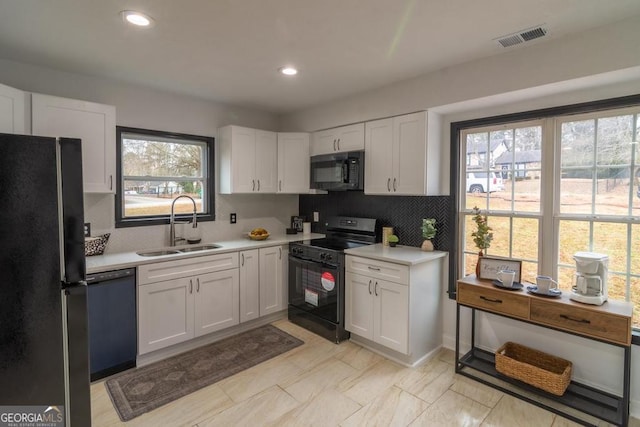 kitchen with sink, black appliances, tasteful backsplash, and white cabinets