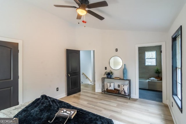 bedroom featuring light wood-type flooring, ceiling fan, lofted ceiling, and ensuite bath