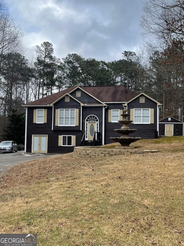 raised ranch featuring driveway and a front lawn