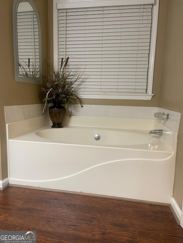 bathroom featuring wood finished floors and a bath