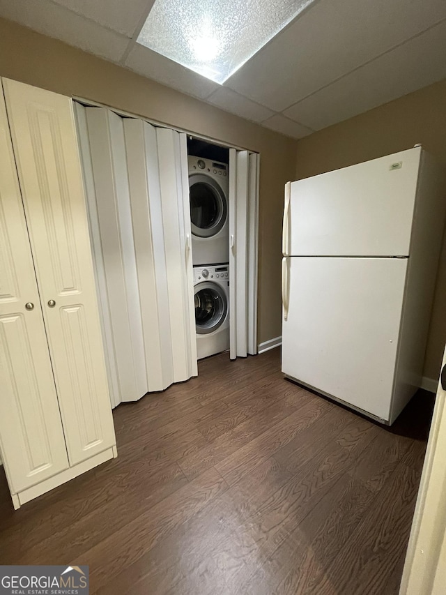 laundry room featuring laundry area, dark wood-type flooring, and stacked washer / dryer