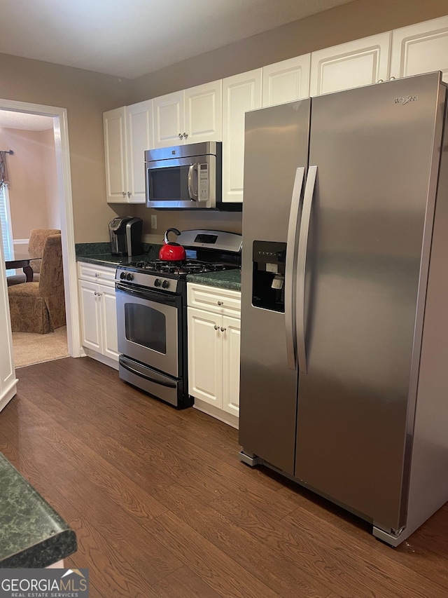 kitchen with dark countertops, white cabinetry, stainless steel appliances, and dark wood-type flooring