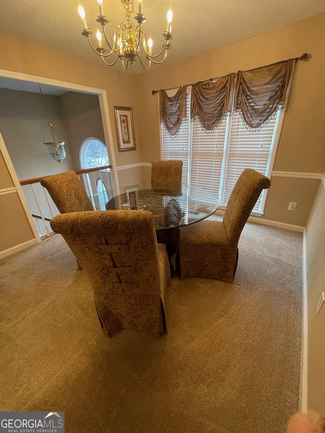 carpeted dining space with a chandelier, a textured ceiling, and baseboards