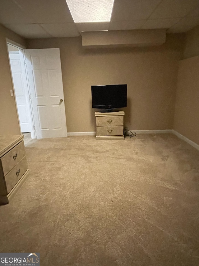 finished below grade area with a paneled ceiling, baseboards, and light colored carpet