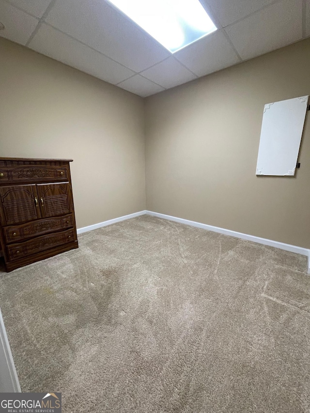 unfurnished room featuring carpet flooring, a paneled ceiling, and baseboards