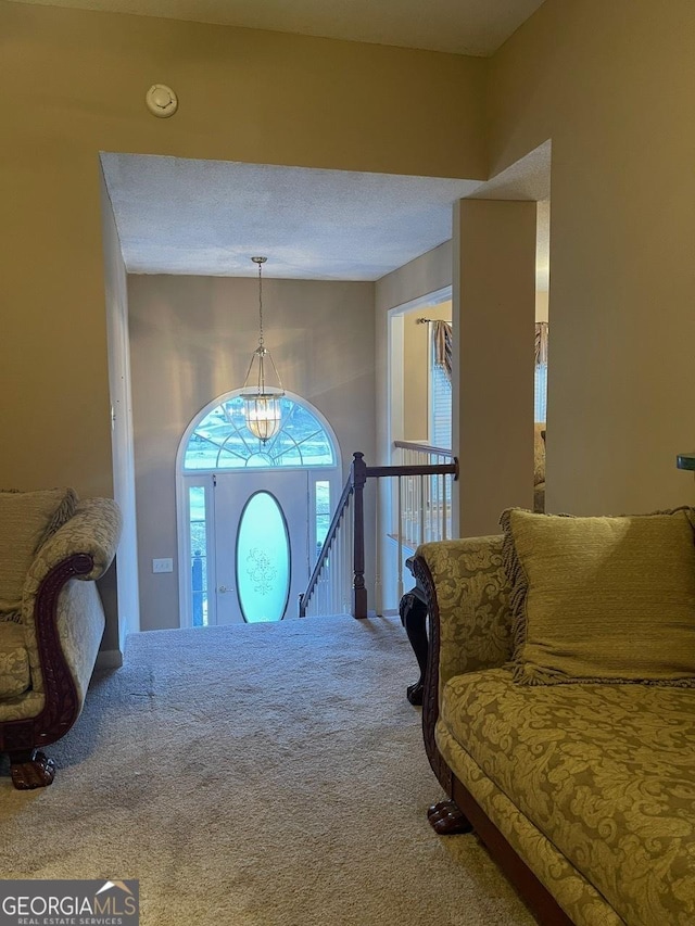 foyer with carpet and a notable chandelier