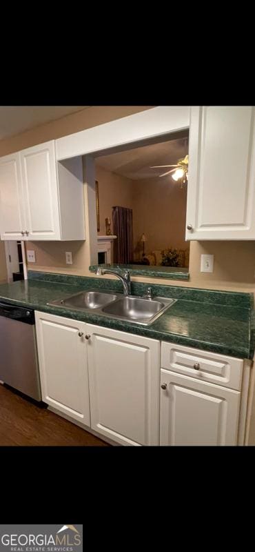 kitchen featuring dishwasher, dark countertops, wood finished floors, white cabinetry, and a sink