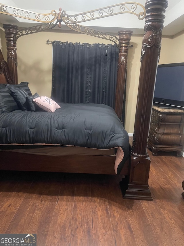 bedroom with dark hardwood / wood-style flooring and ornate columns