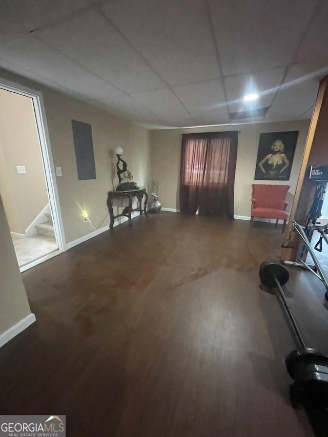 interior space with a drop ceiling, wood finished floors, and baseboards