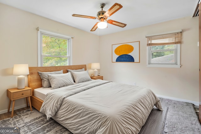 bedroom with wood-type flooring, multiple windows, and ceiling fan