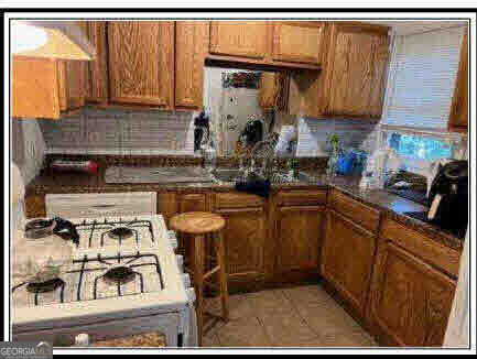 kitchen with decorative backsplash, white gas range oven, and light tile patterned floors