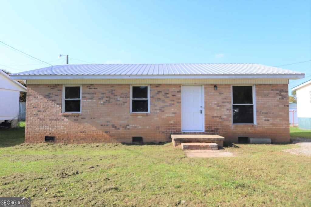 view of front of property with crawl space, brick siding, metal roof, and a front yard