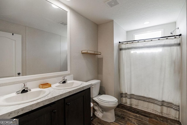 bathroom with hardwood / wood-style flooring, vanity, a textured ceiling, toilet, and walk in shower