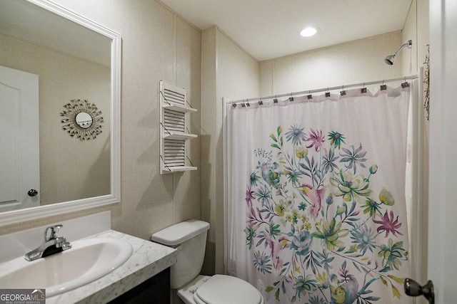 bathroom with walk in shower, vanity, and toilet