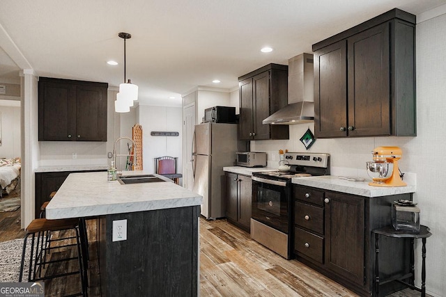 kitchen featuring wall chimney exhaust hood, stainless steel appliances, a kitchen breakfast bar, and a center island with sink